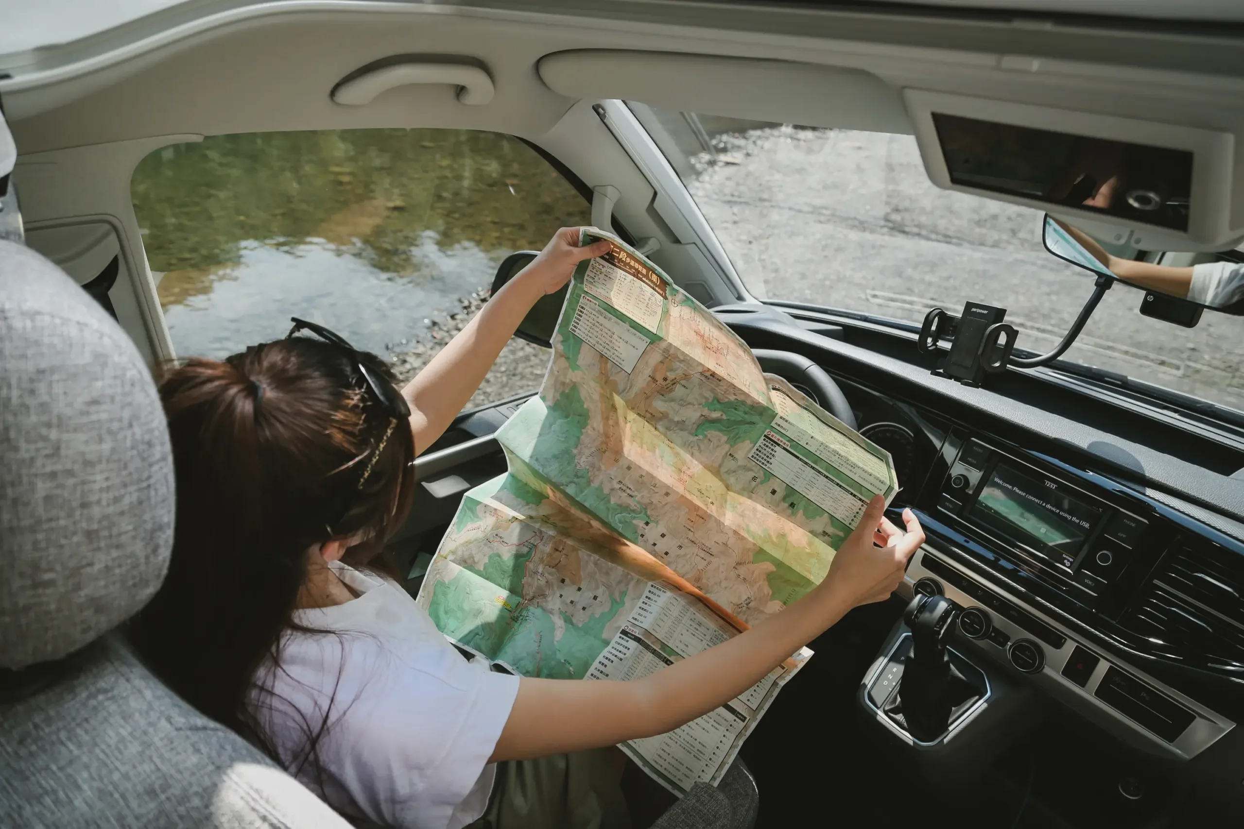 一個女生坐在露營車內看著地圖